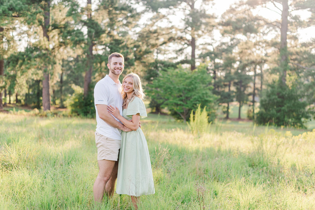 engaged couple standing in a field at Lake Gaston 