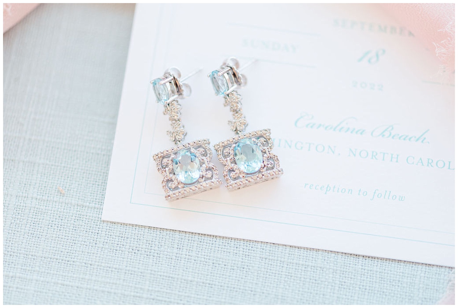crystal and light blue earrings sitting on a invitation suite