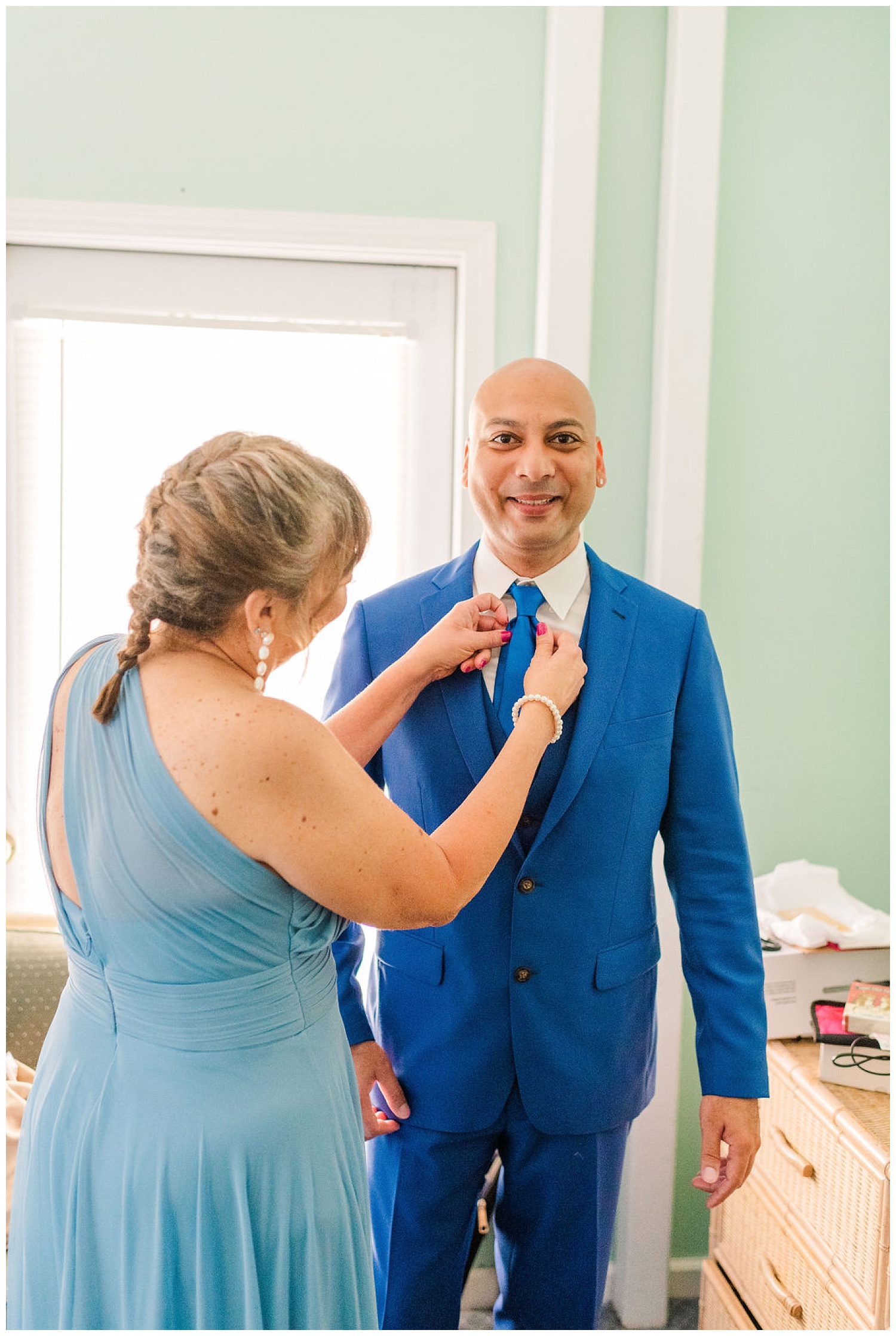 groom getting his tie adjusted while getting ready before the wedding