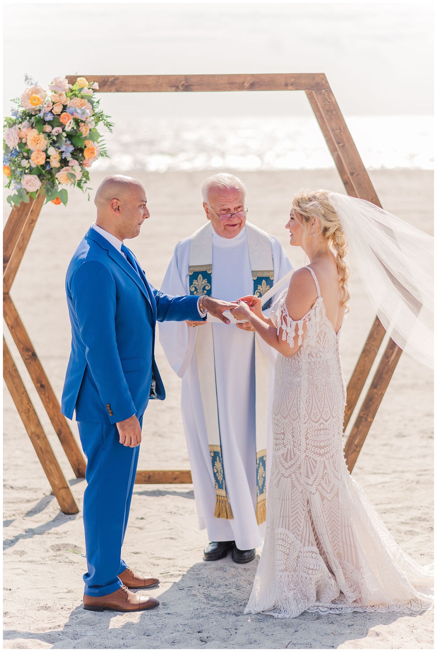 bride putting on the groom's ring at wedding ceremony on the beach