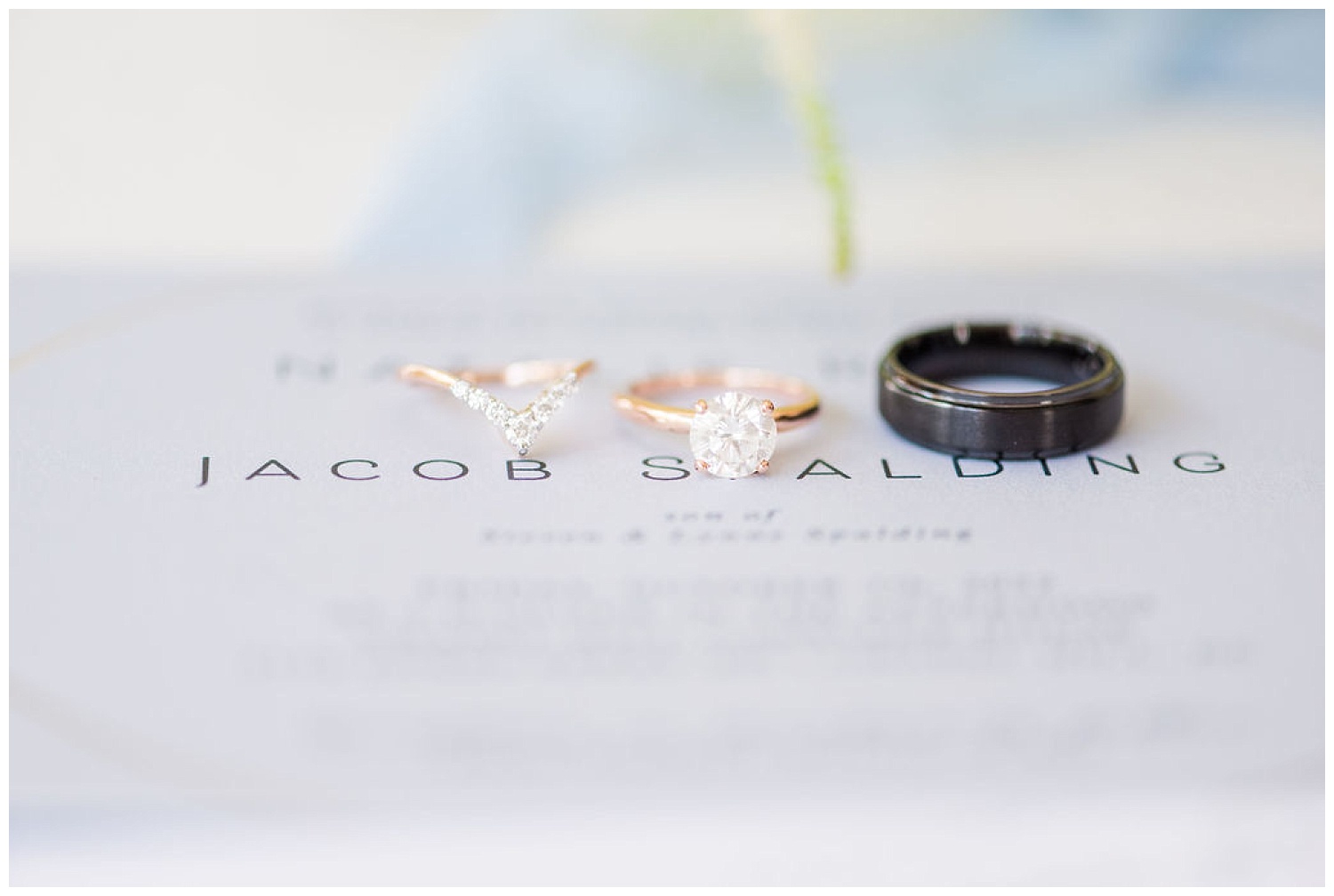 wedding rings sitting on top of an invitation