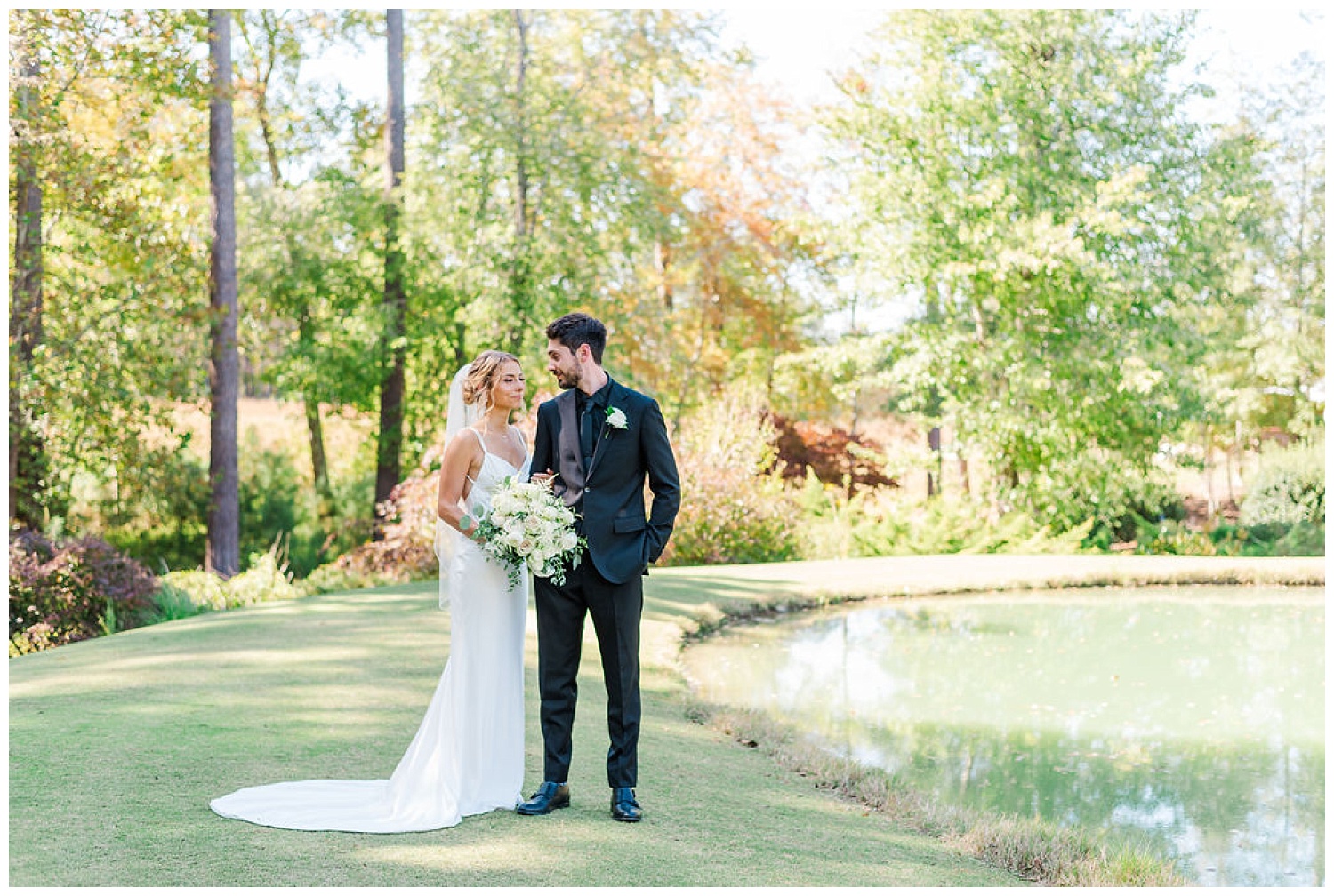 wedding couple posing next to a pond at the Chapel Hill Carriage House