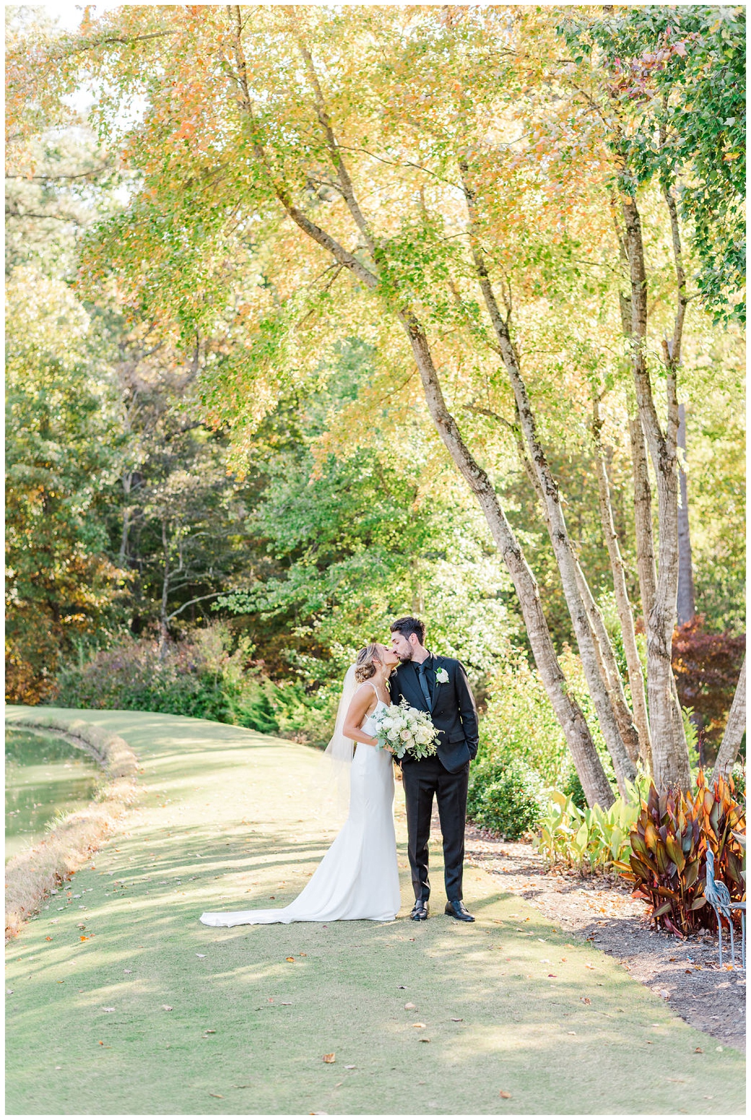 bride and groom kissing under a large tree in Chapel Hill