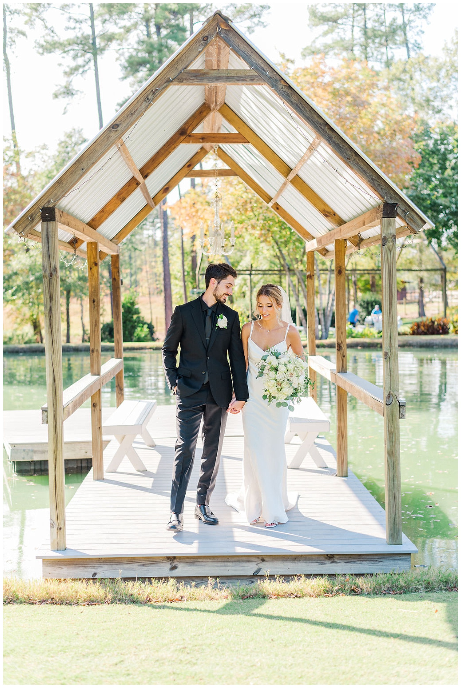 bride and groom posing under a canopy on a dock