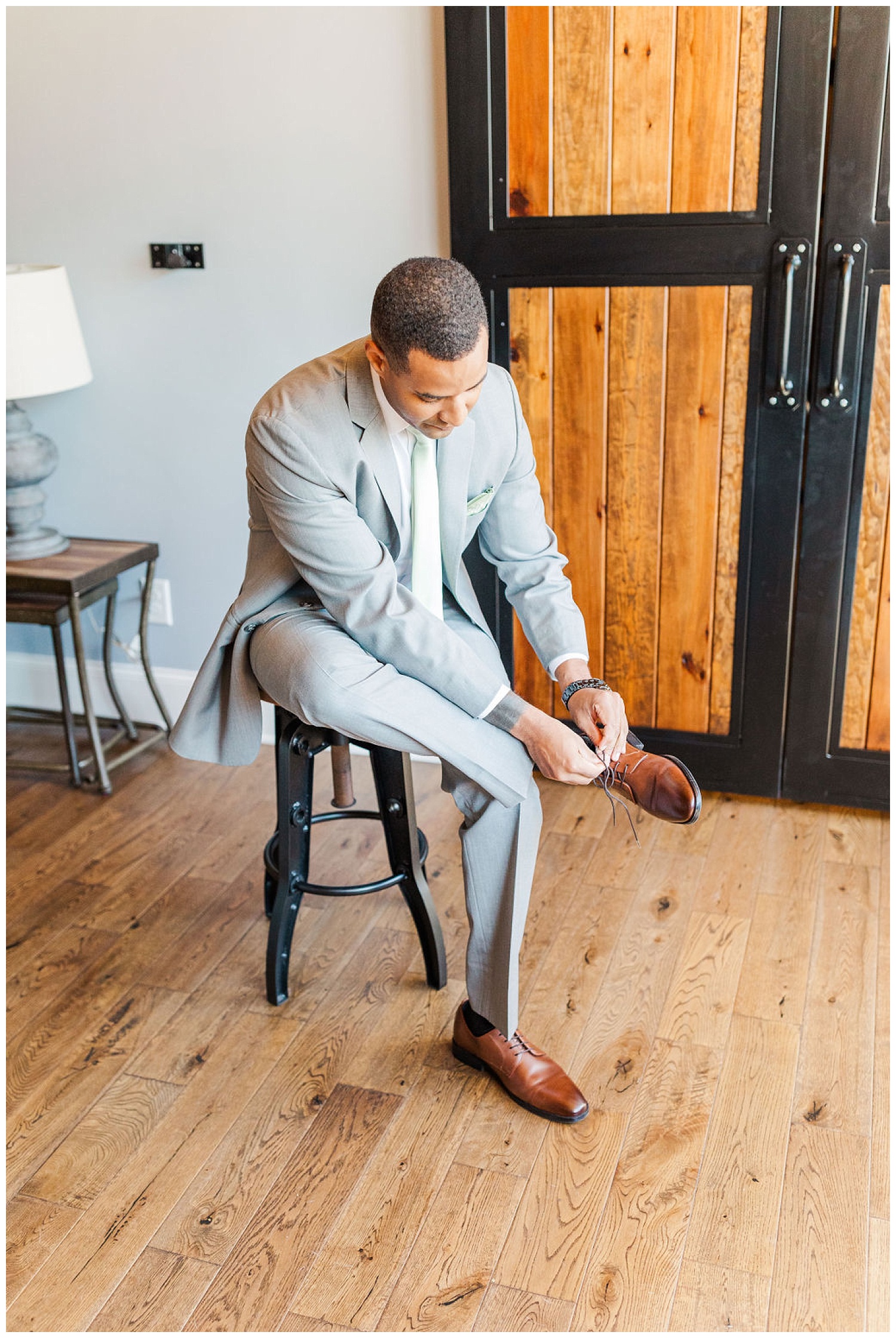 groom adjusting his shoes while getting ready at wedding