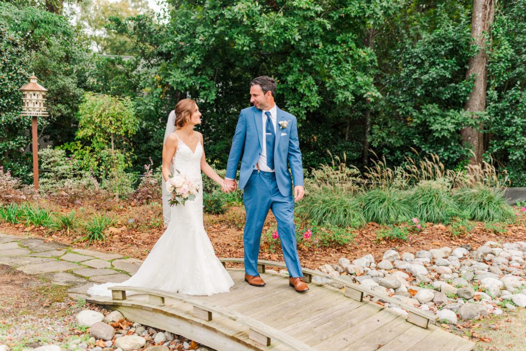 bride and groom walking across the bridge at Hew Hanover County Arboretum