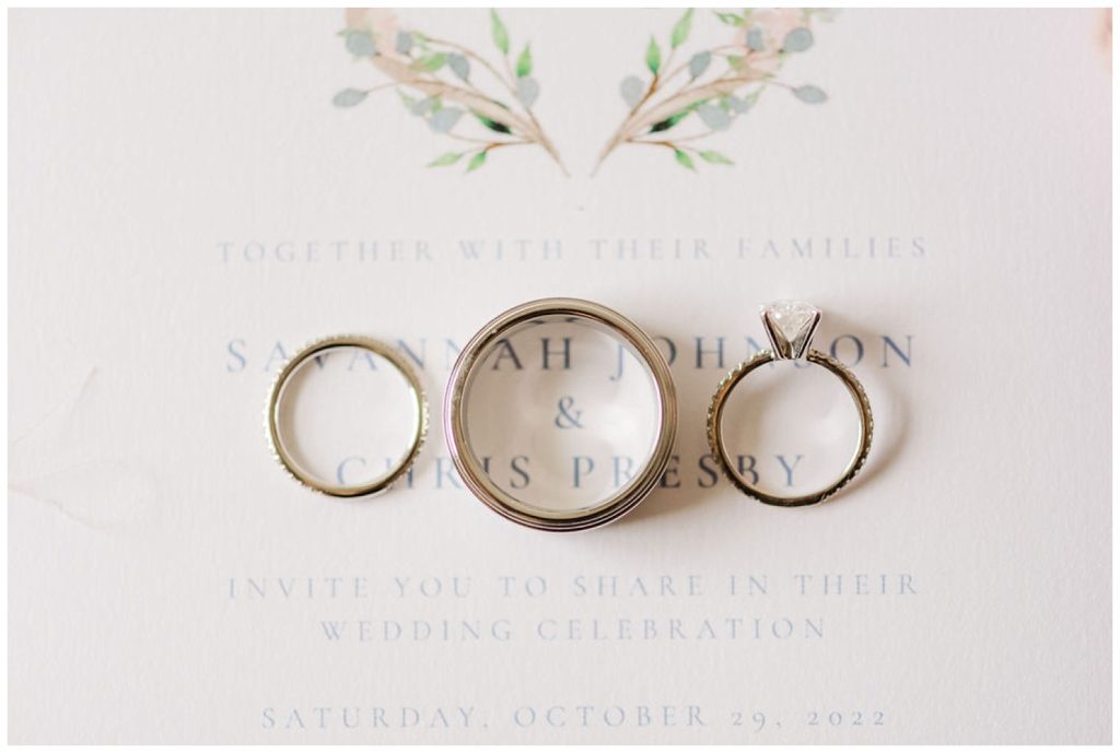 three wedding rings lined up on top of invitation in Wilmington