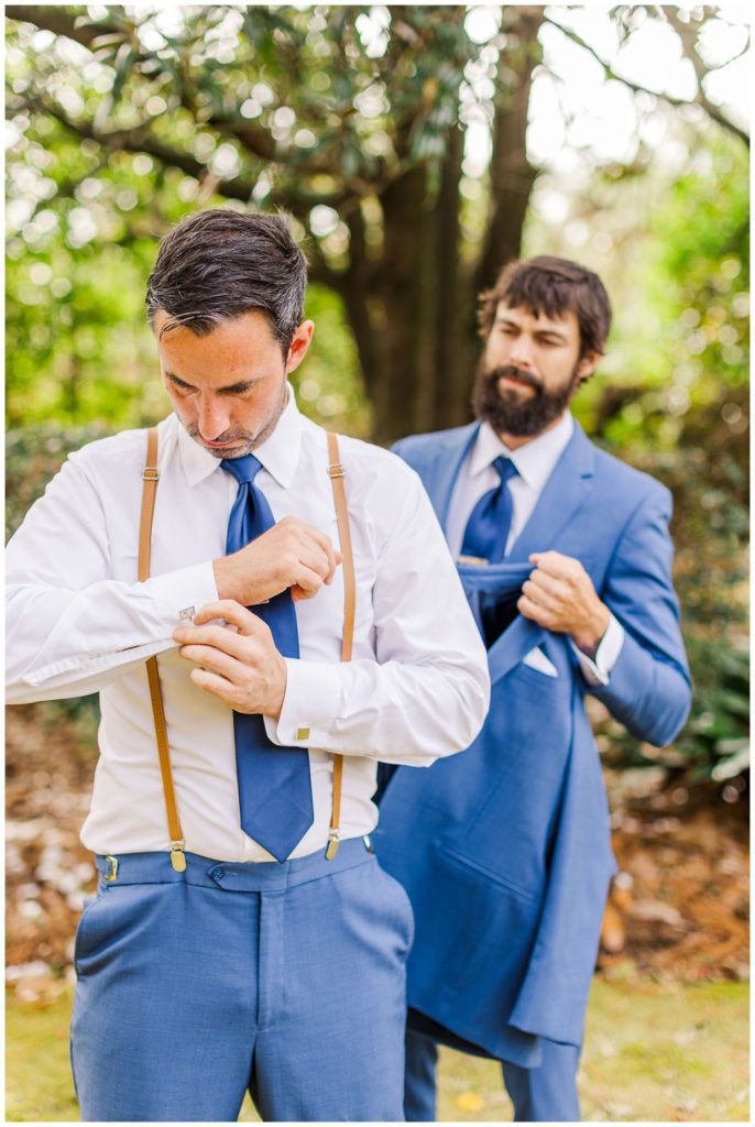 groom adjusting his suit  outside before wedding ceremony 