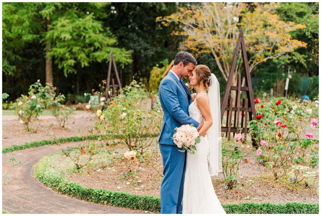 wedding couple standing in front of flowers at New Hanover County Arboretum in Wilmington, NC