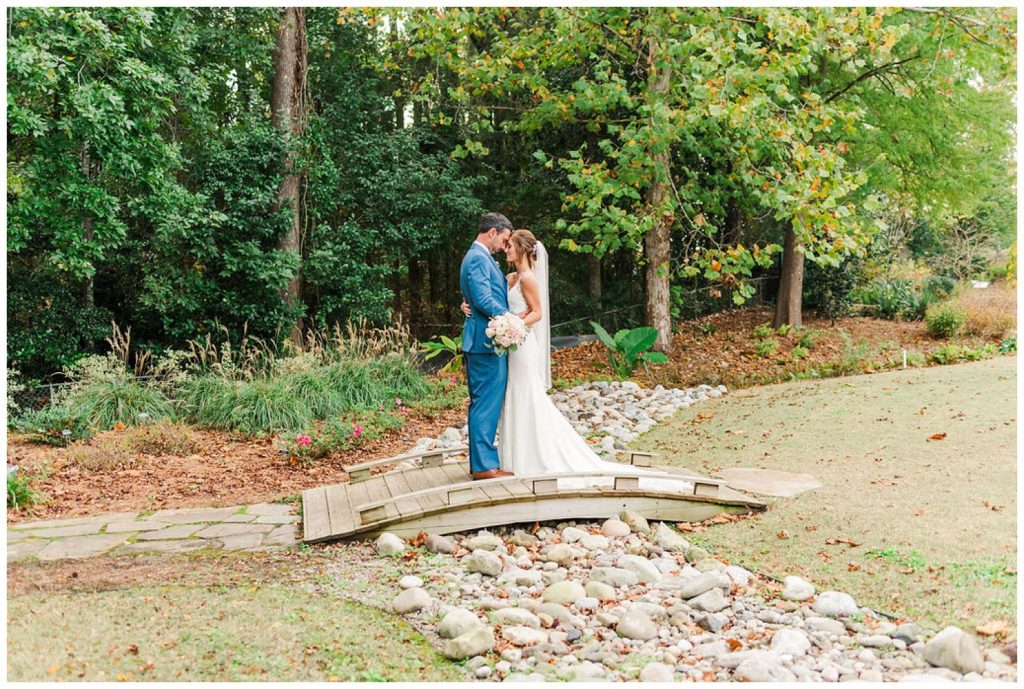 wedding couple standing on a bridge at New Hanover County Arboretum