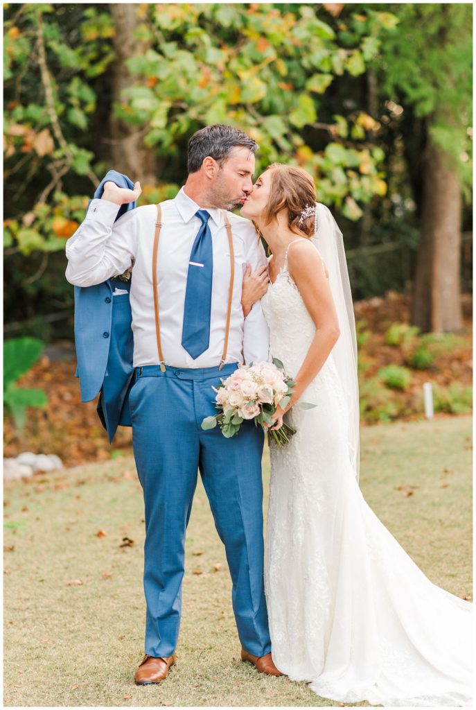 groom holding his jacket while kissing his bride at Wilmington NC wedding