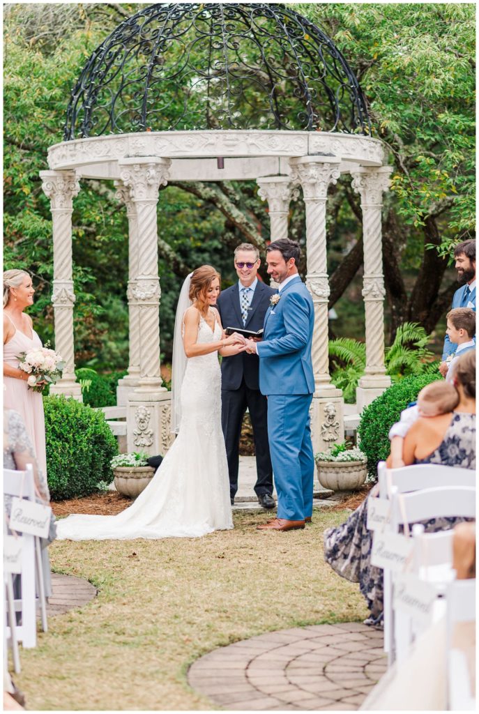 bride and groom exchanging rings at New Hanover County Arboretum