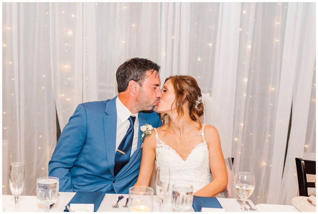 bride and groom kissing at table during wedding reception