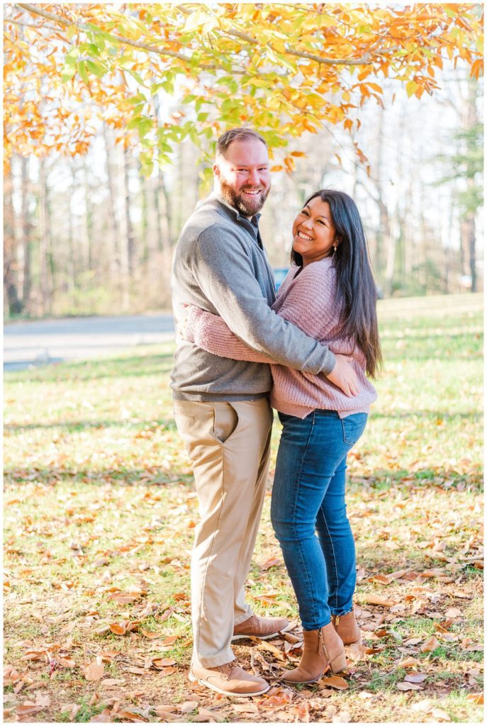 engaged couple posing for photos in front of a yellow and orange tree