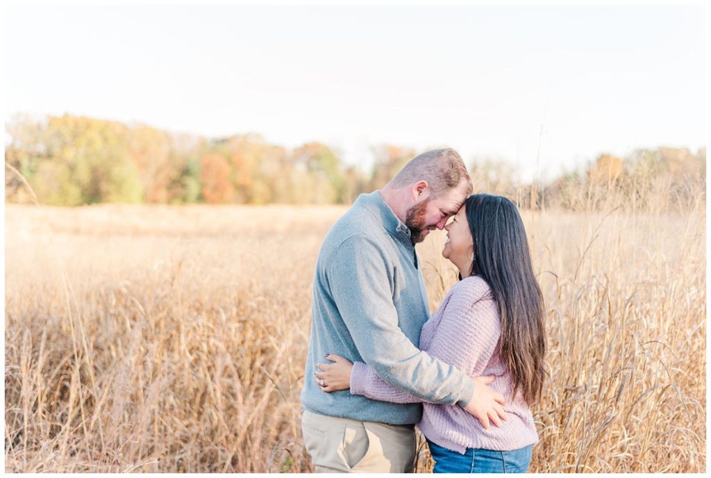 engaged couple touching foreheads in a field at Reynolda