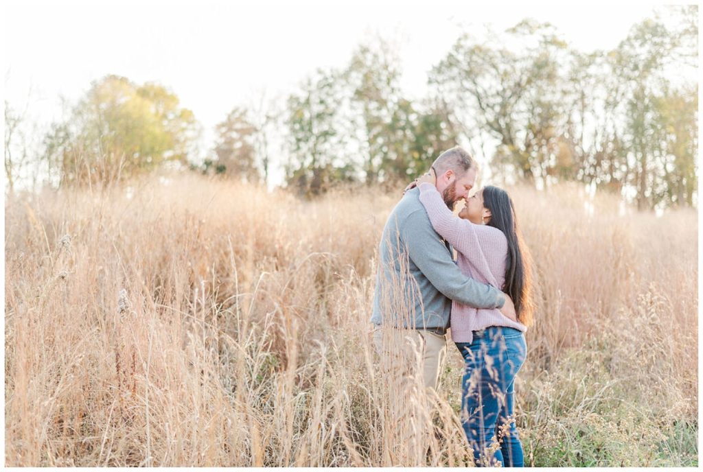 couple standing in a field touching noses at Winston-Salem engagement session