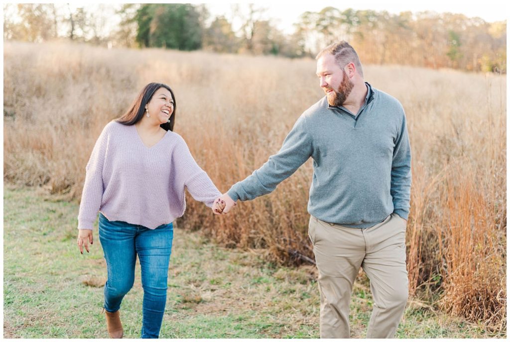 couple holding hands in a field at fall engagement session in North Carolina