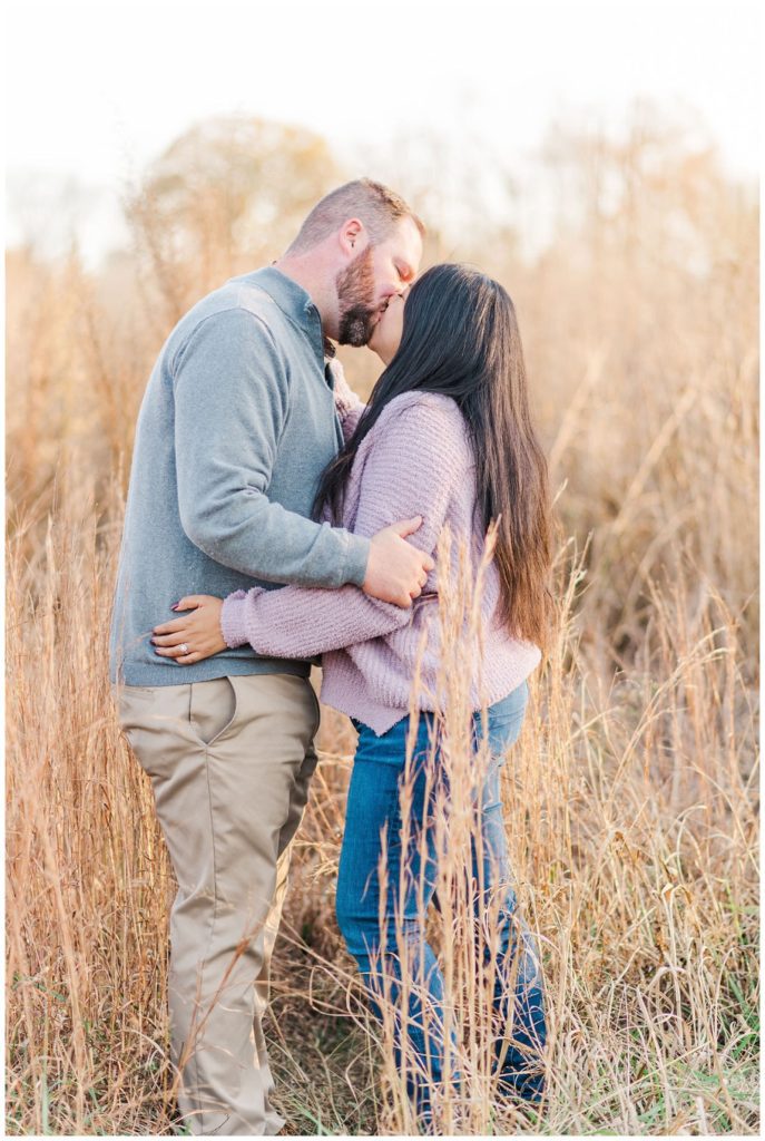 couple kissing in a wheat field during fall engagement session