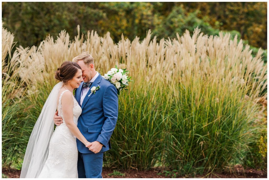 bride and groom posing in front of tall grass 
