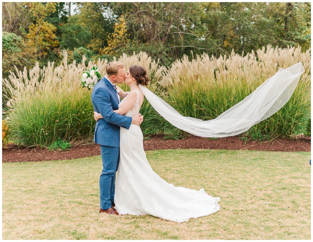bride's veil flying while kissing groom at fall wedding