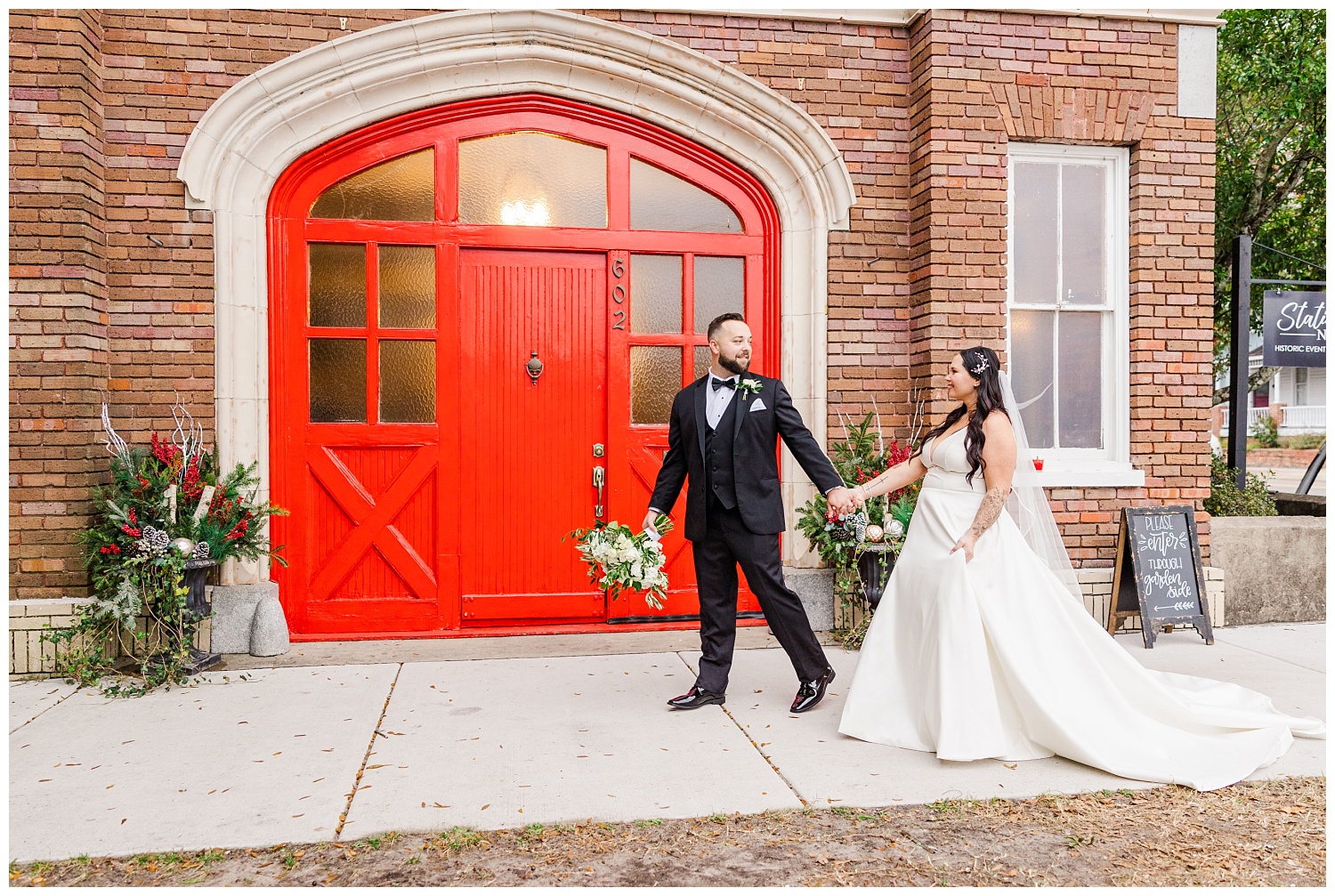 bride and groom walking in front of the red doors at Station No.2
