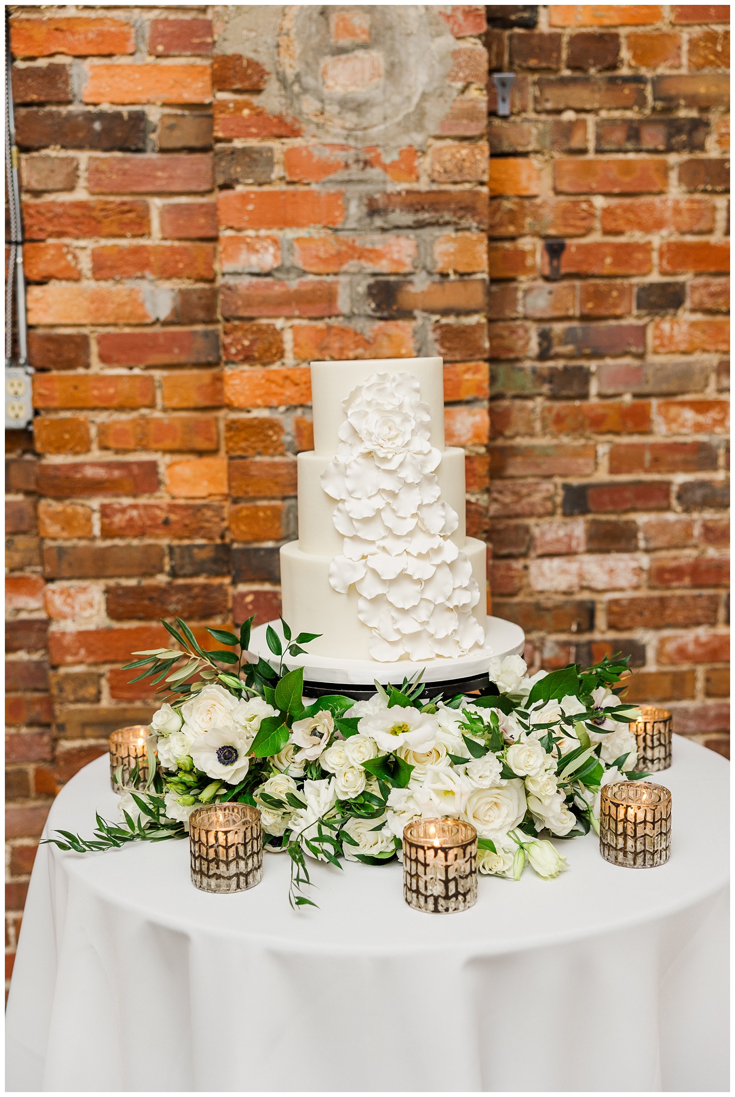 wedding cake against a brick wall at winter wedding reception