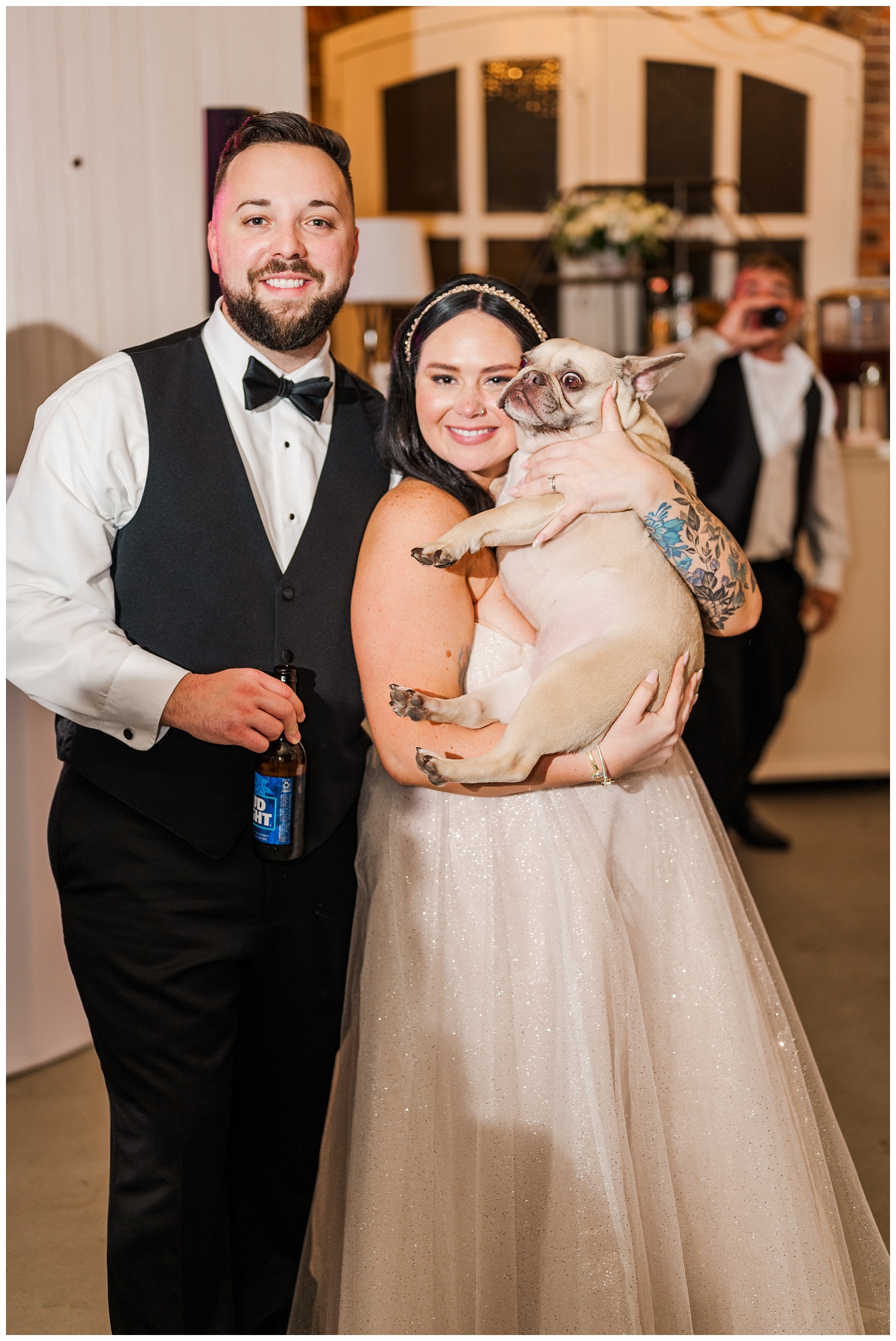 bride and groom holding their dog at wedding reception
