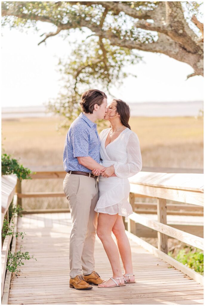 engaged couple kissing on a boardwalk at Fort Fisher
