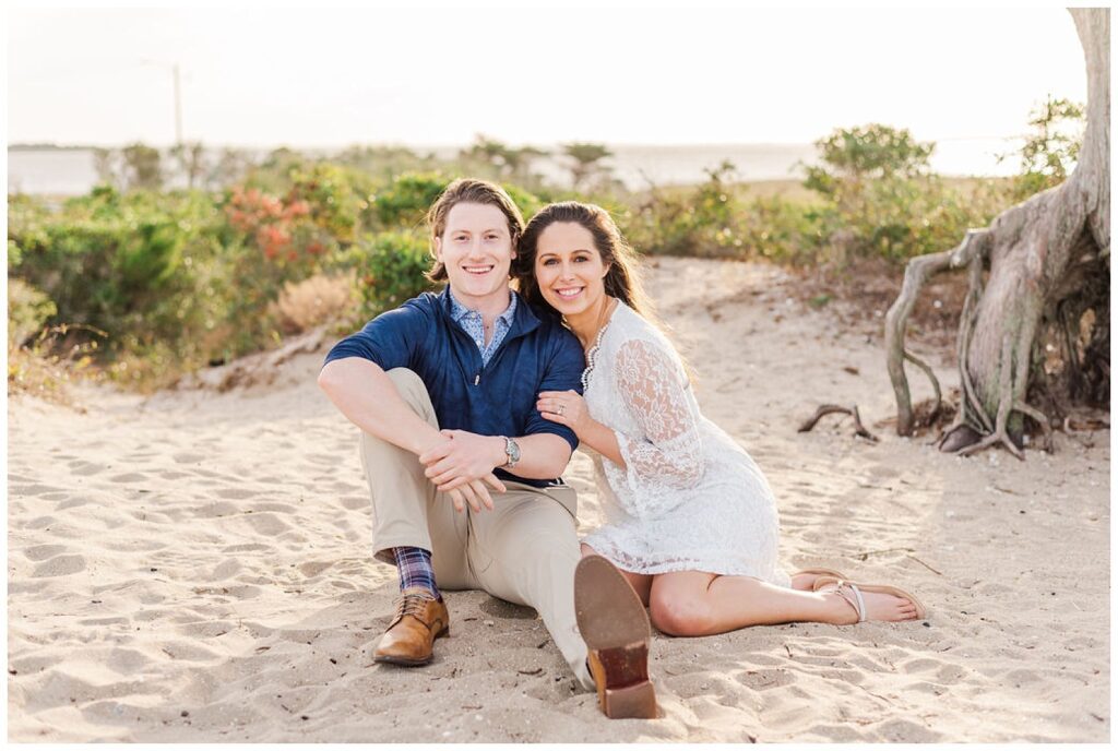 couple sitting on the beach for engagement photos in NC