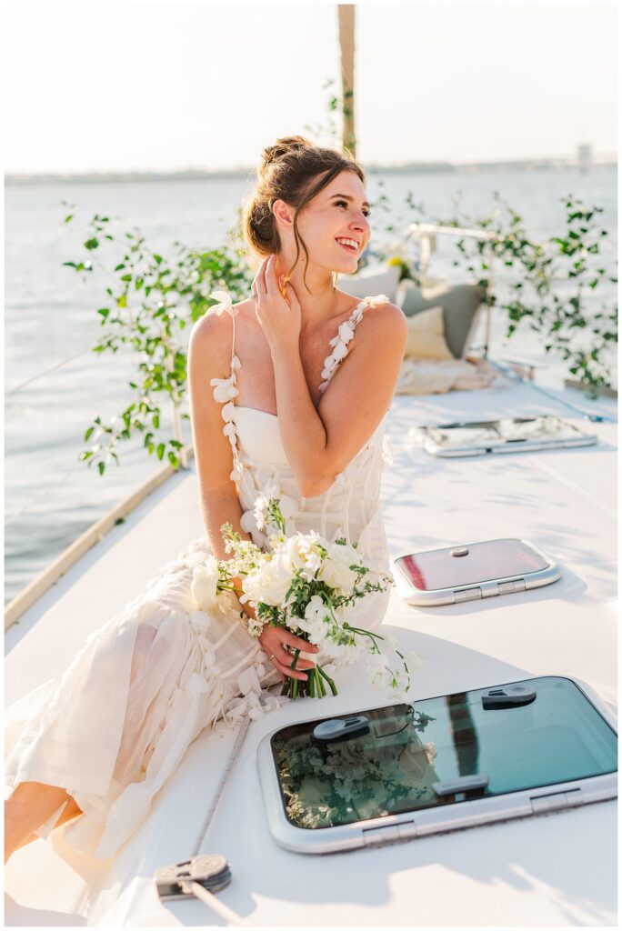 bride holding a bouquet sitting on a sailboat 
