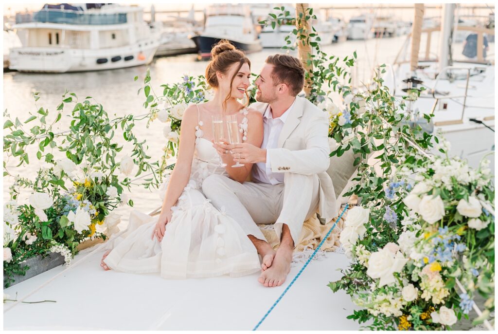 elopement couple laughing and toasting champagne on a sailboat