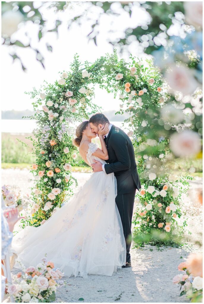 bride and groom kissing under a floral arch at Charleston wedding venue
