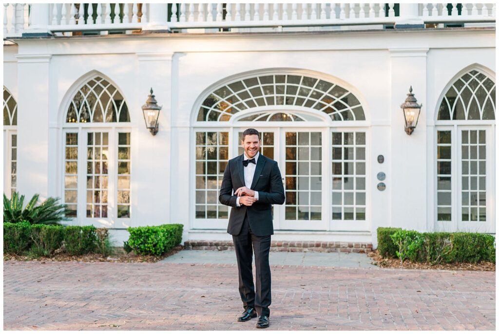 groom adjusting cuff links at front of entrance at Charleston wedding venue
