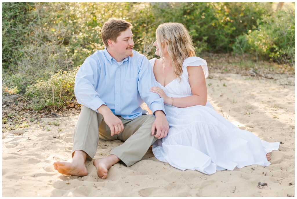 couple sitting on the sand at Fort Fisher engagement session