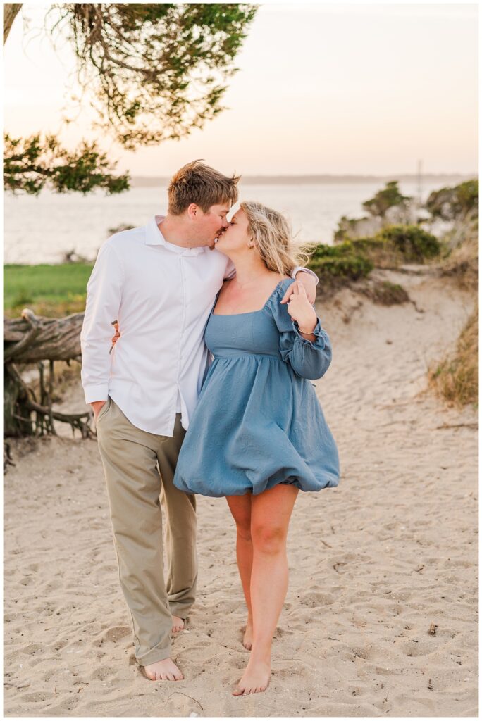couple kissing and walking on the beach at Fort Fisher engagement