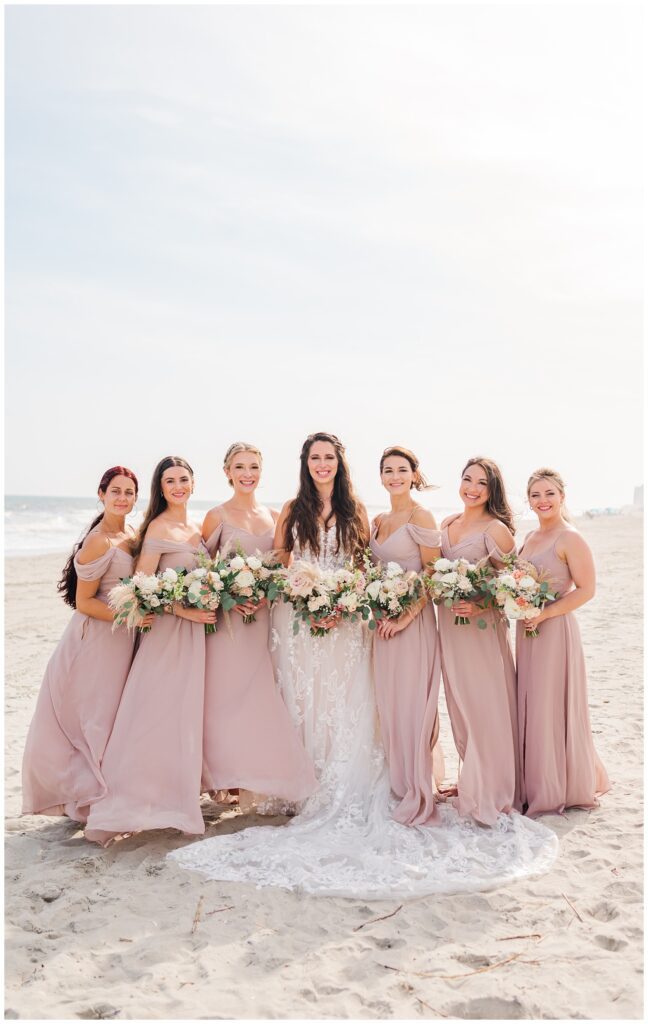 bride and bridesmaids posing on the beach for wedding