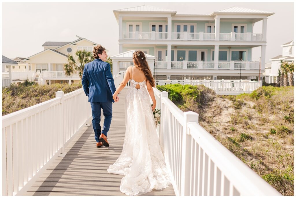 bride and groom walking together on the dock at beach front house 
