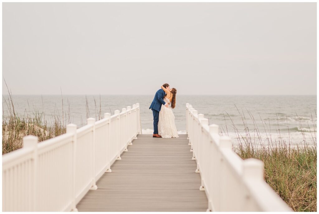 bride and groom kissing on the dock at Ocean Isle, NC
