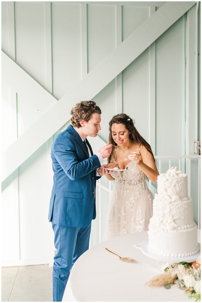 bride and groom cut wedding cake at beach front reception