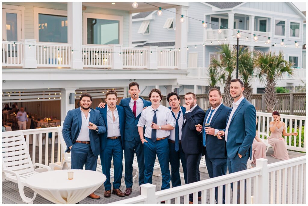 groom posing with groomsmen and friends at beach wedding