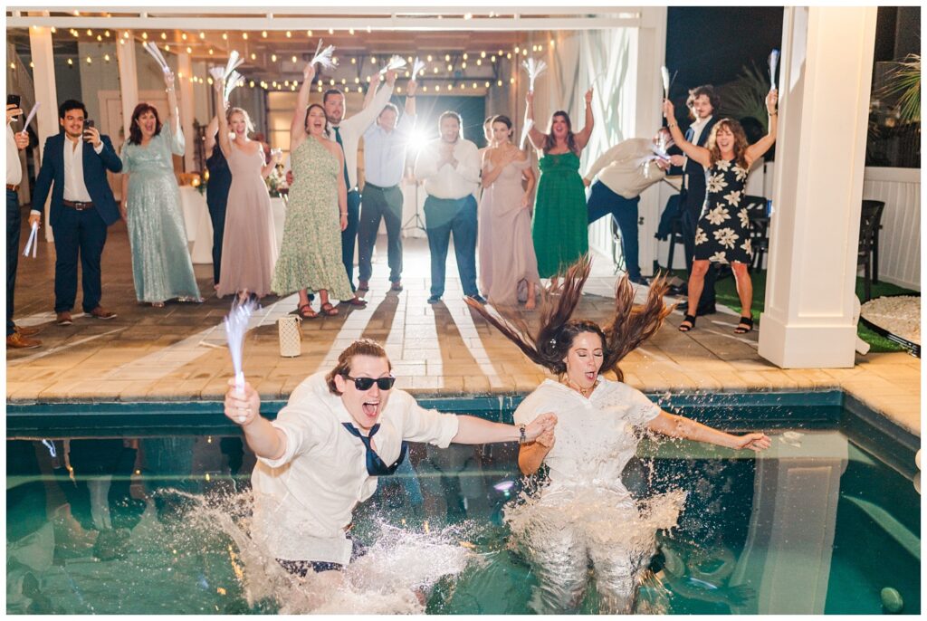 bride and groom jumping into pool at beach house reception