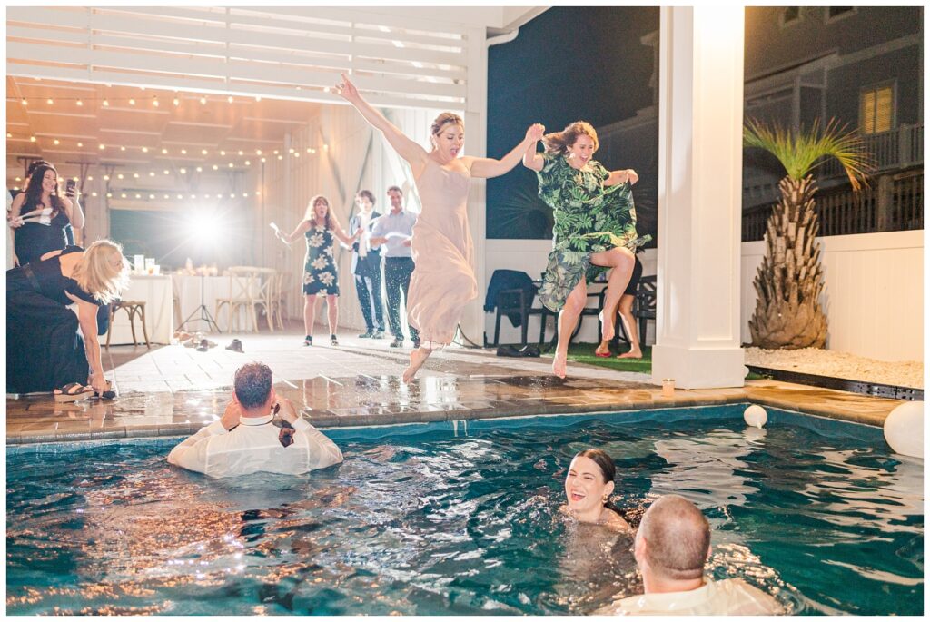 wedding guests jumping into pool at reception 