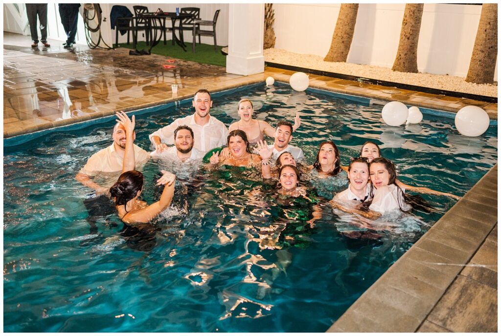 wedding guests jumping into pool at beach house reception