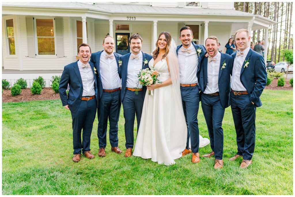 bride posing with groomsmen on the front lawn in North Carolina