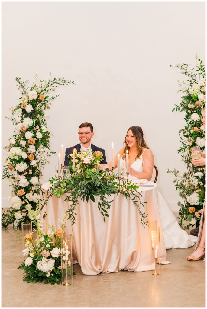 bride and groom sitting at sweetheart table at spring wedding reception