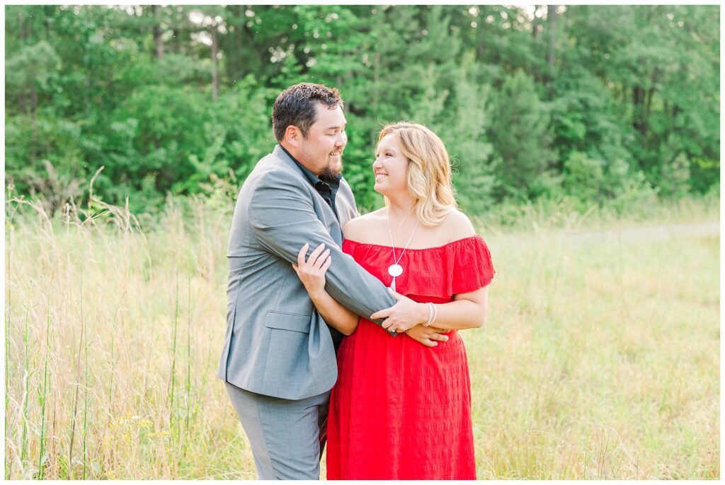 engaged couple wearing a gray suit and red dress on a farm in Fayetteville