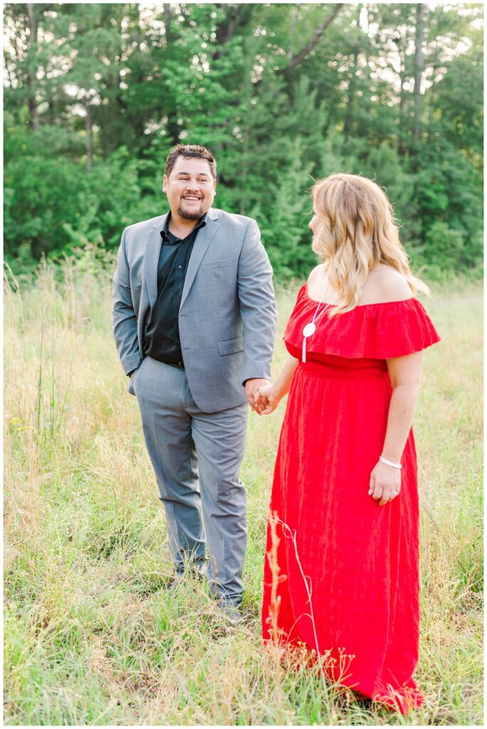engaged couple wearing a gray suit and red dress on a farm in Fayetteville