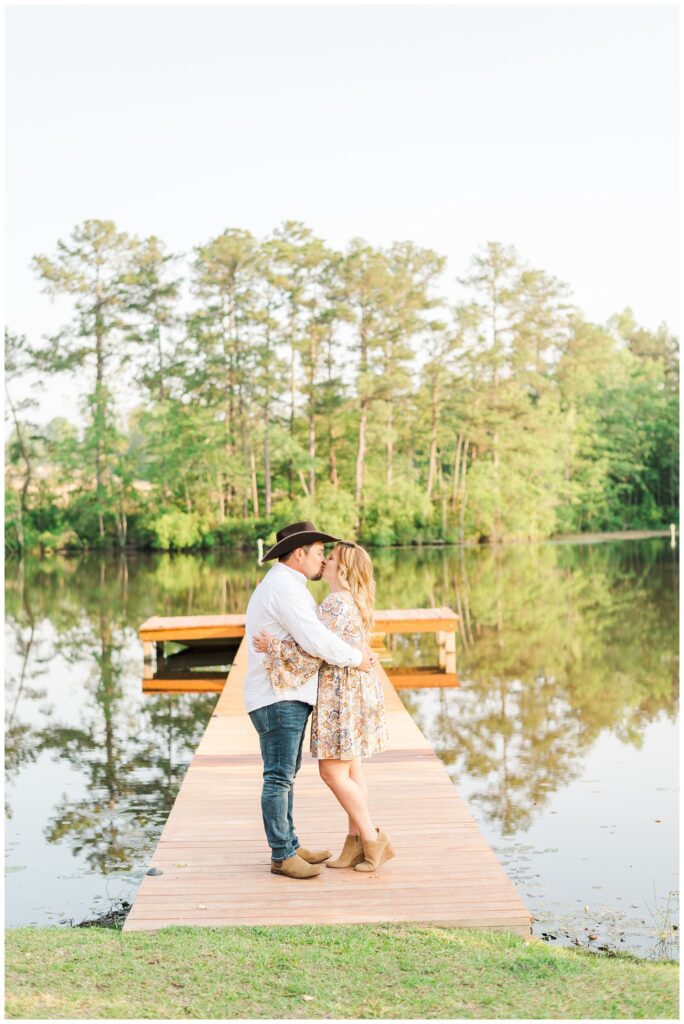 couple kissing on a dock on a pond at engagement session
