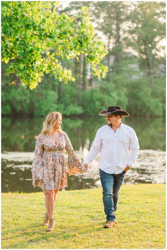 couple posing for engagement session under a tree next to pond