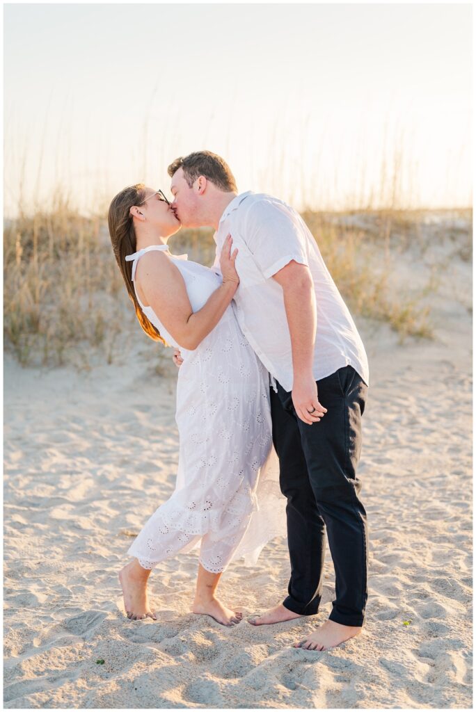 husband and wife kissing on the sand at Wrightsville Beach